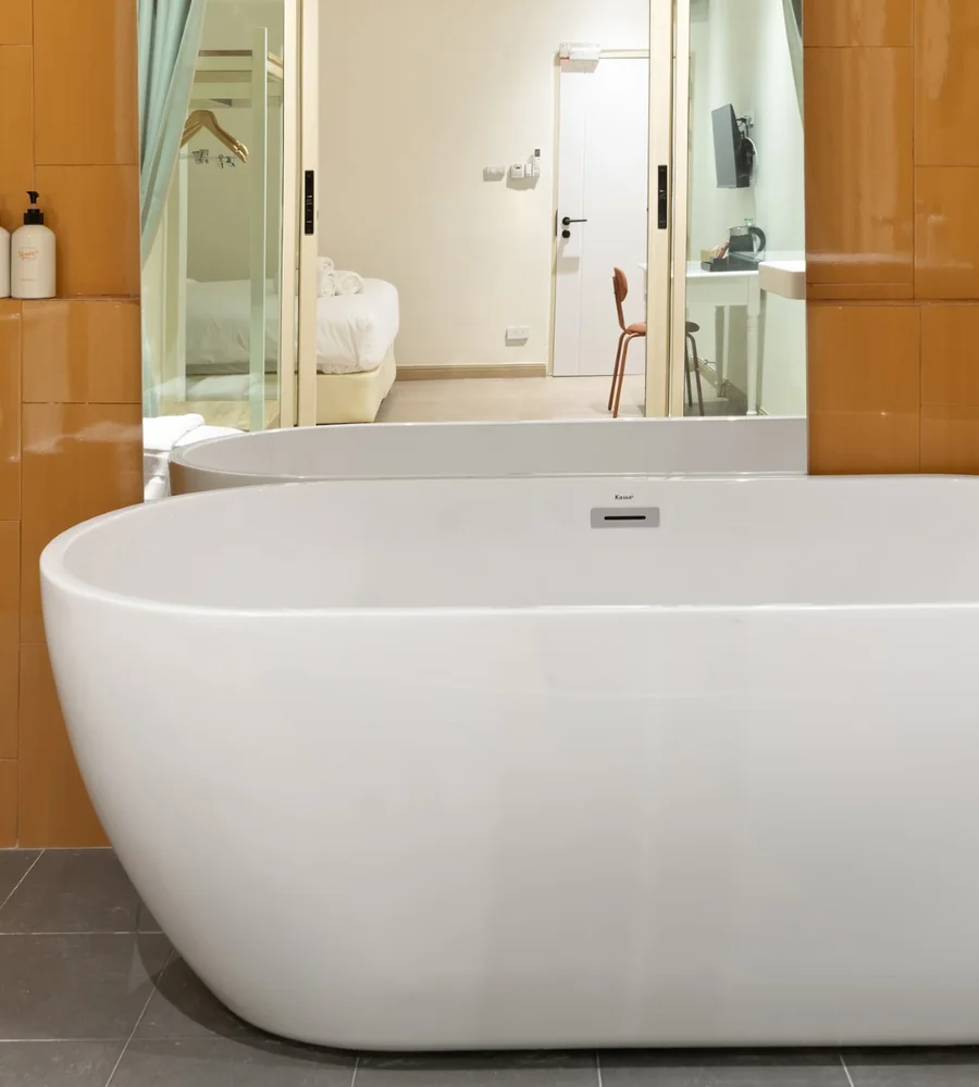Freestanding bathtub and rain shower in the Deluxe with Bathtub room at Horange Phuket Town, with burnt orange tiling