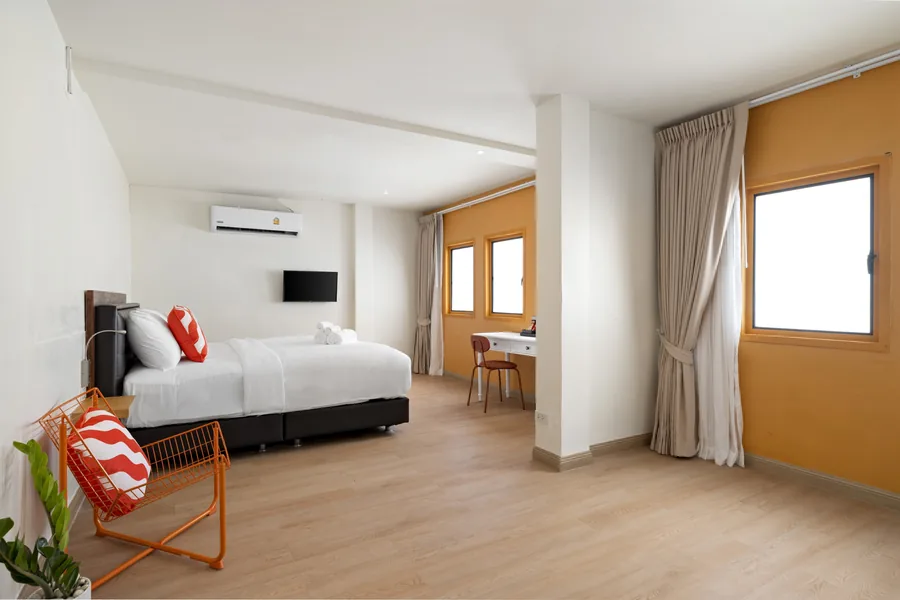 Studio room at Horange Phuket Town with a queen bed, a desk and an orange feature wall