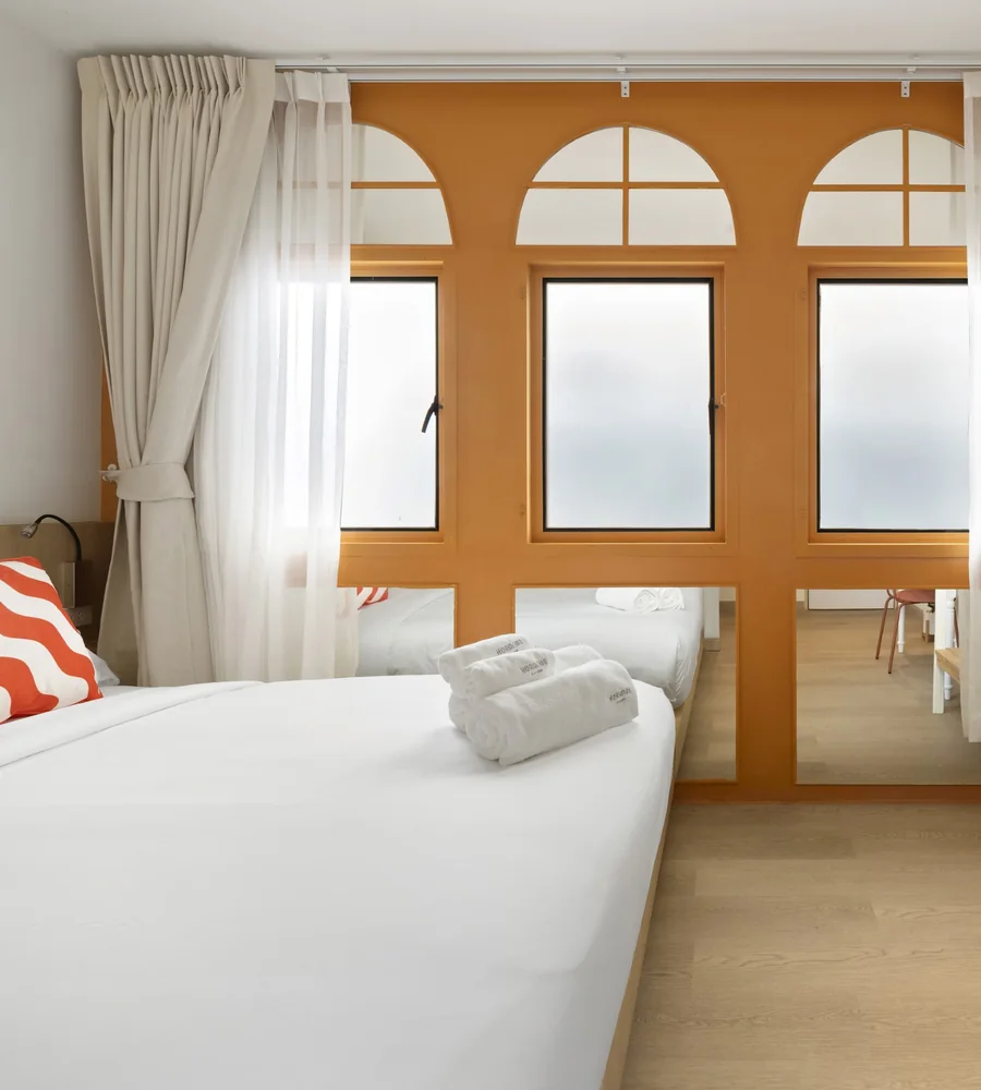 Superior room at Horange Phuket Town with three arched windows set into an orange wall beside the bed
